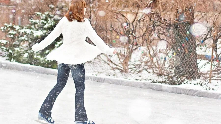 A beginner ice skater practicing on an outdoor ice rink, focusing on balance and technique
