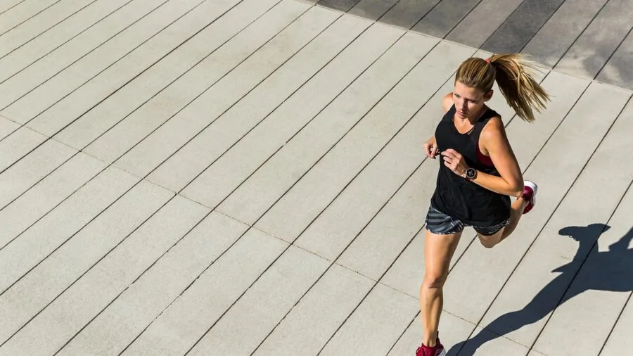 Active jogger adjusting gear pockets during outdoor run on sunny path