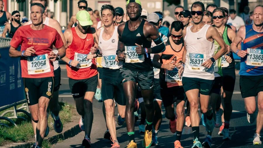 Active runner wiping sweat from forehead while jogging on sunny trail
