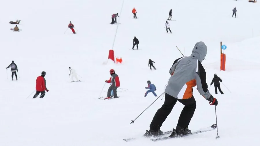Active skier descending snowy mountain slope in winter gear
