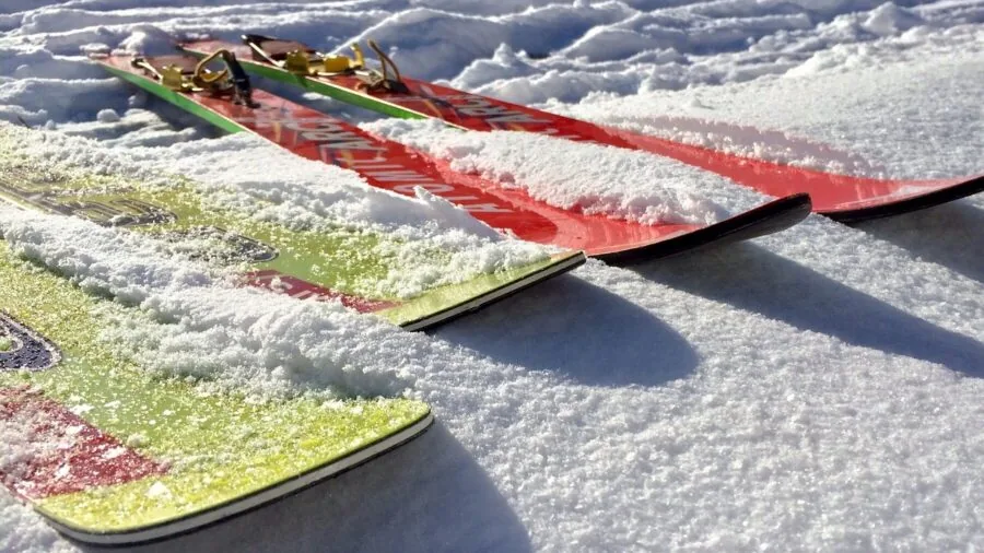 Active skier descending snowy slope in bright sunlight wearing winter sports gear