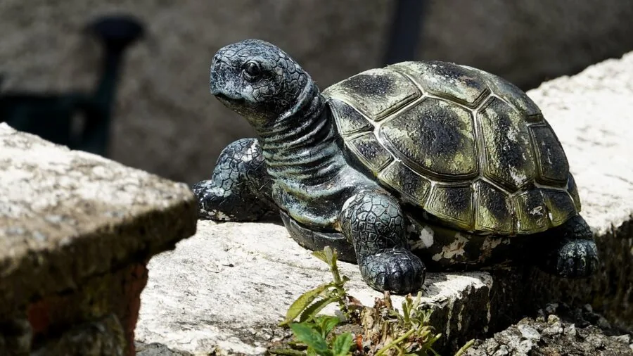 Aged stone garden statue standing in natural outdoor setting with weathered patina and moss growth