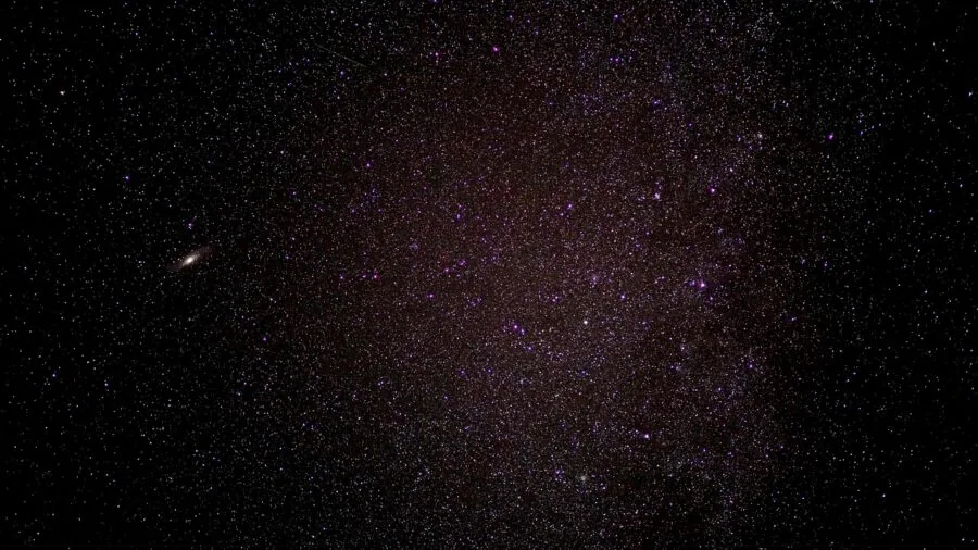 Amateur astronomer observing stars through telescope under clear night sky