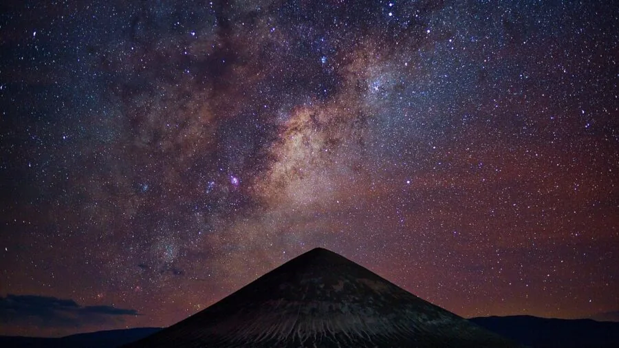 Amateur astronomer observing stars through telescope under night sky