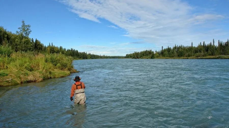 Angler casting fishing line in cold winter water conditions