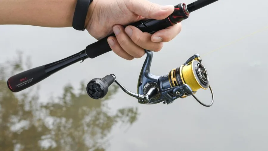 Angler casting spinning reel while fishing in freshwater lake at sunrise