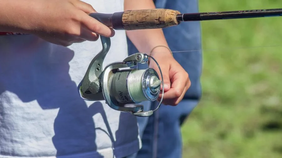 Angler examining fishing reel frame and rotor construction in natural daylight