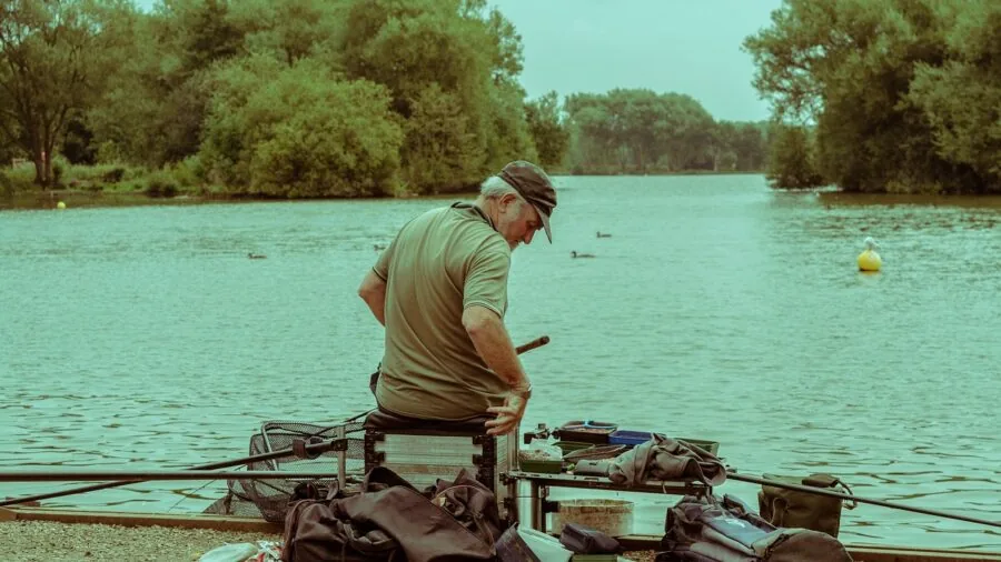 Angler holding fishing rod by calm water in natural outdoor setting