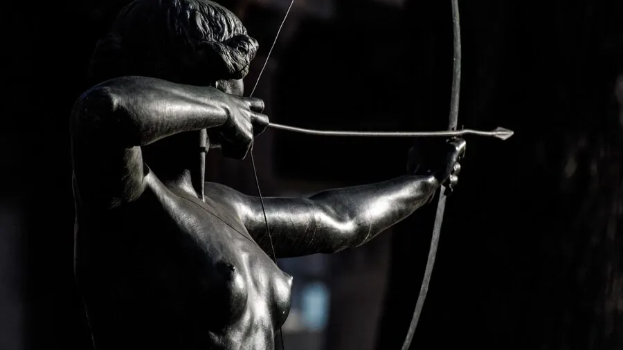 Archer in natural setting drawing compound bow with focus and concentration during outdoor practice