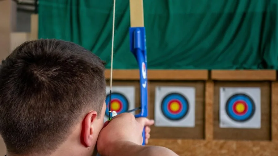 Archer in outdoor setting practicing with crossbow in natural landscape