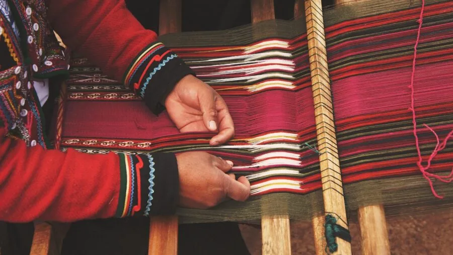 Artisan examining woven fabric texture in natural light, showcasing traditional textile craftsmanship and quality materials