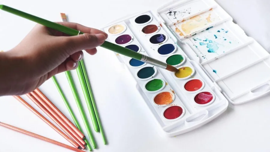 Artist applying paint to canvas surface, showing texture and weave detail during creative work