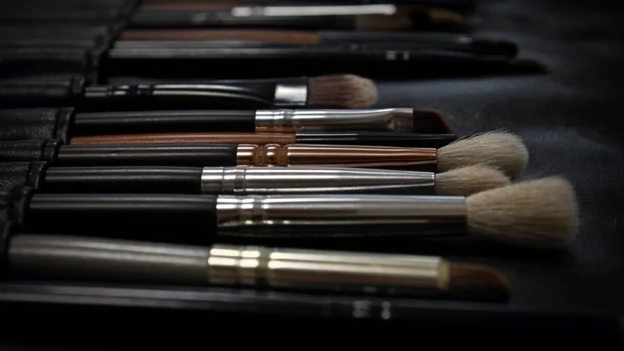 Artist cleaning paintbrushes at wooden table in natural light studio workspace