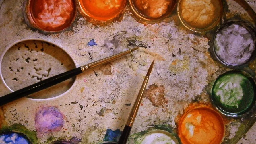 Artist mixing watercolors on palette with brush, demonstrating color blending technique