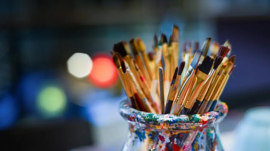 Artist using airbrush equipment for detailed painting work in creative studio space