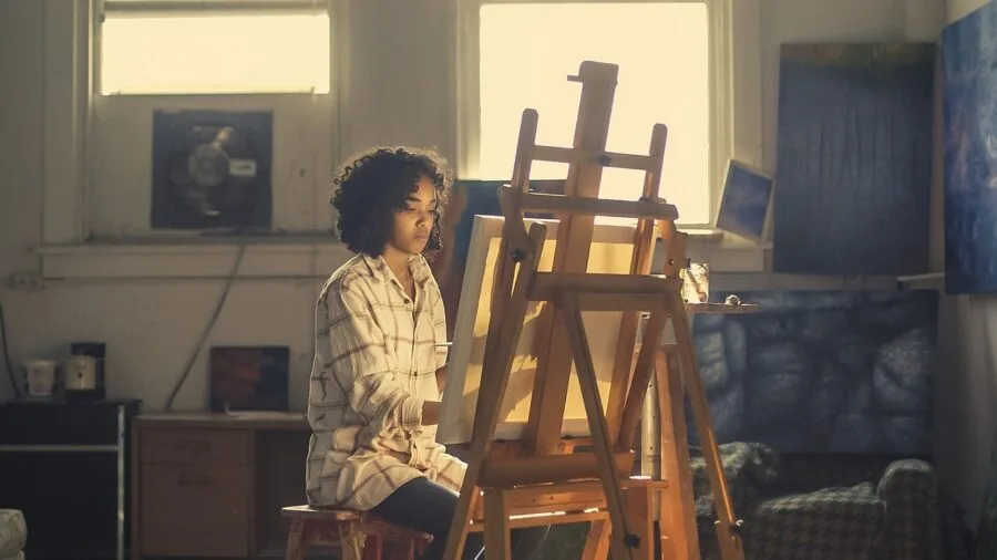 Artist working at wooden easel in bright studio with natural light
