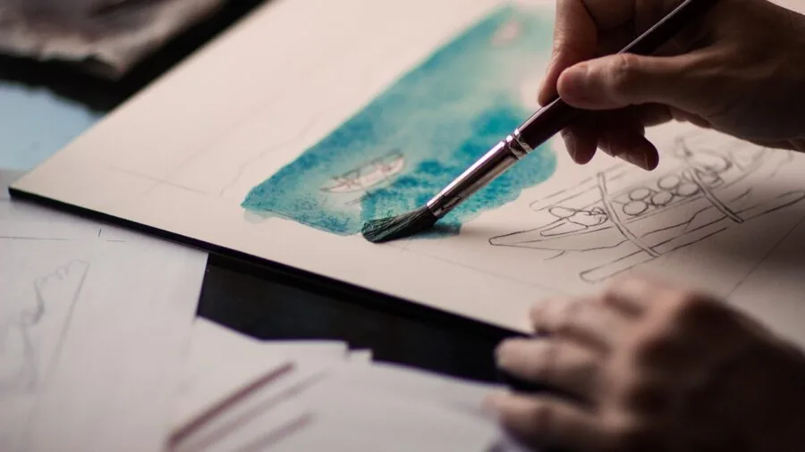 Artist working with acrylic paints on different materials including canvas, wood and paper