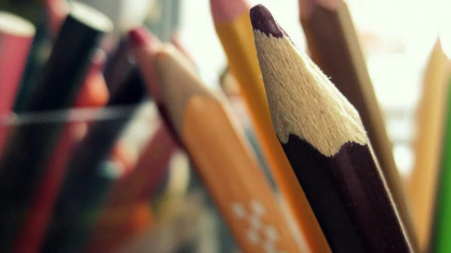 Artist's desk with colored pencils, sketchbook, and creative materials in natural workspace setting