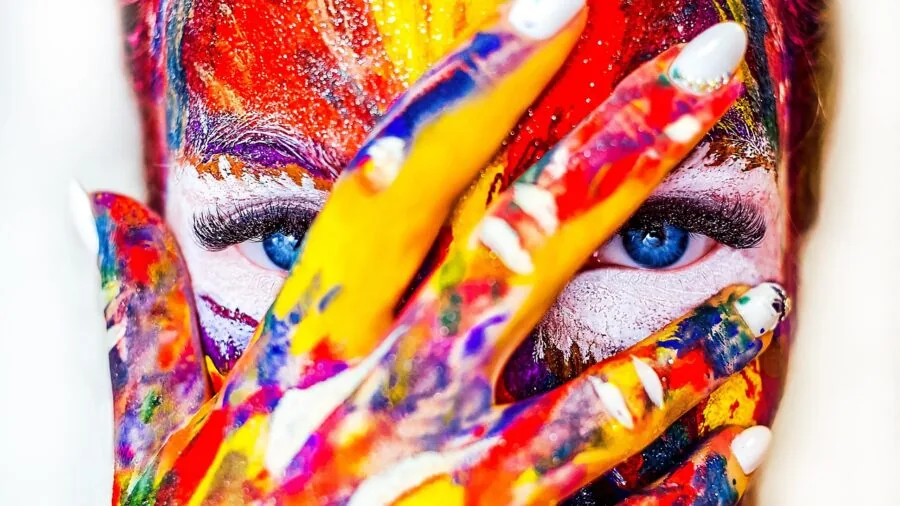 Artist's hand applying rich, saturated colored pencil strokes on paper during creative work
