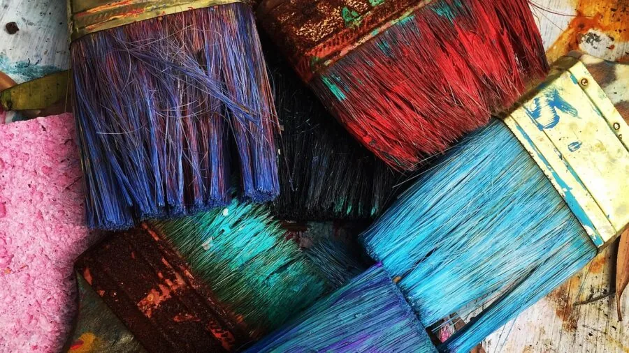 Artist's hands blending colorful oil paints on wooden palette during creative painting session