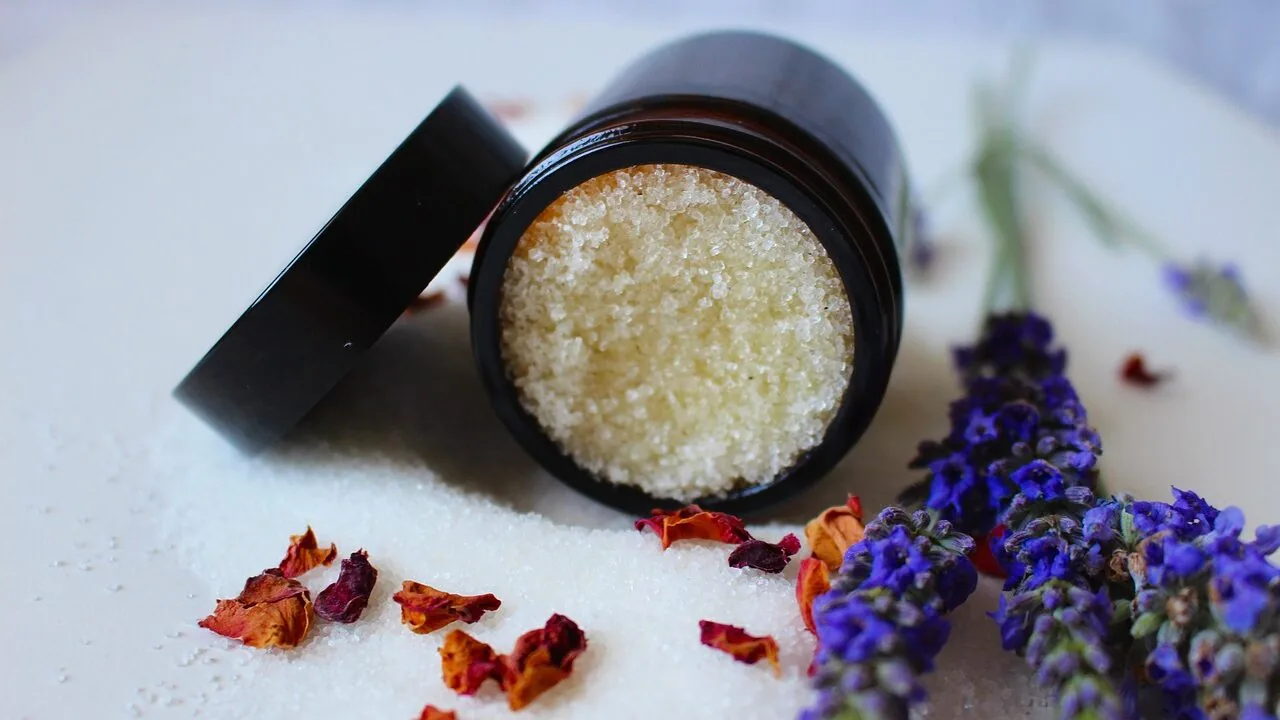 Assorted body scrub jars and containers displayed on a bathroom shelf with natural lighting