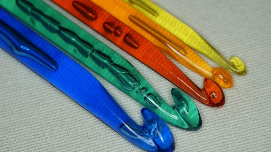 Assortment of colorful crochet hooks in various sizes arranged on a wooden surface for crafting