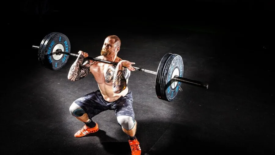 Athlete performing barbell lift in modern gym setting with proper form and weight setup