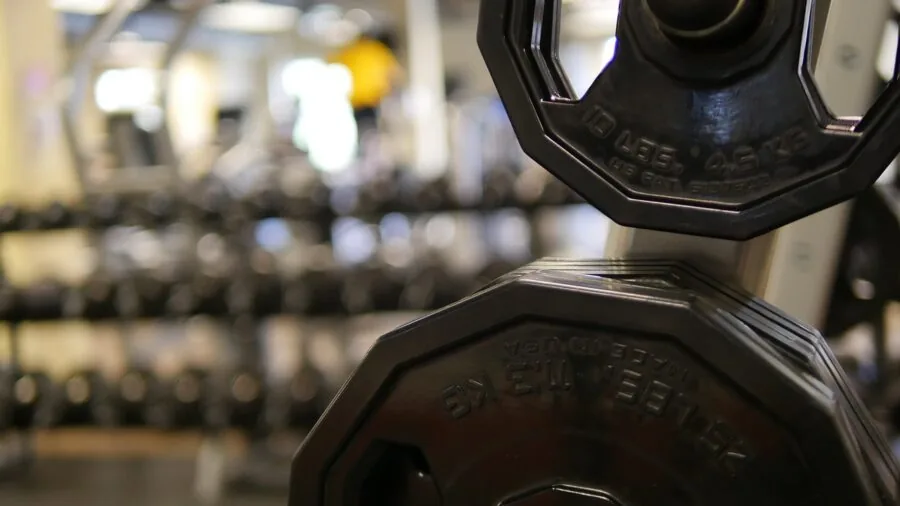 Athlete performing heavy barbell lift in gym setting, demonstrating strength and proper form