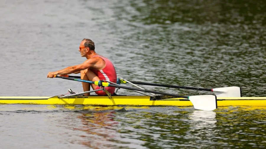 Athlete using rowing machine with focused intensity during indoor fitness training session