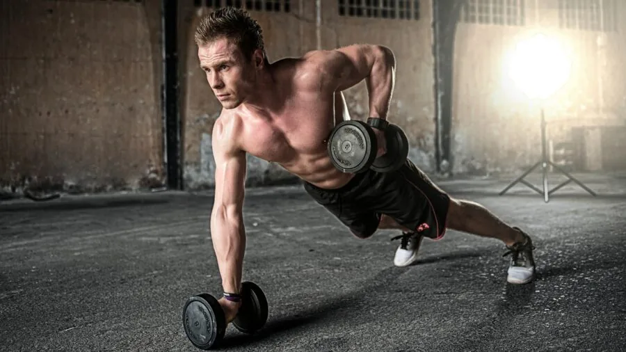 Athletic man performing barbell squat exercise in gym setting with focused form