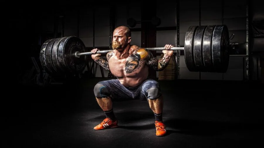 Athletic man wiping sweat from forehead during intense gym training session