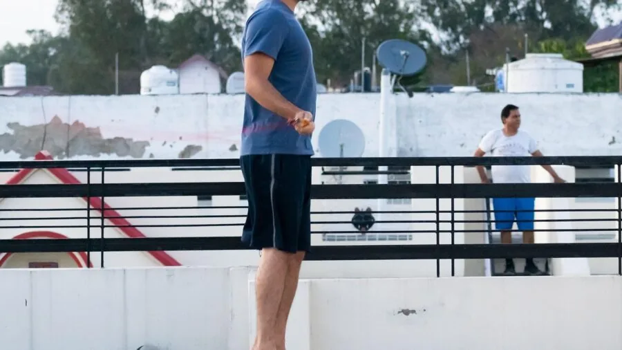 Athletic person performing jump rope exercise outdoors with focused intensity and proper form