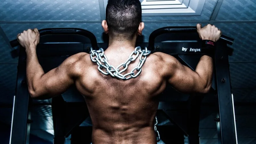 Athletic person performing pull-up on outdoor bar during workout session