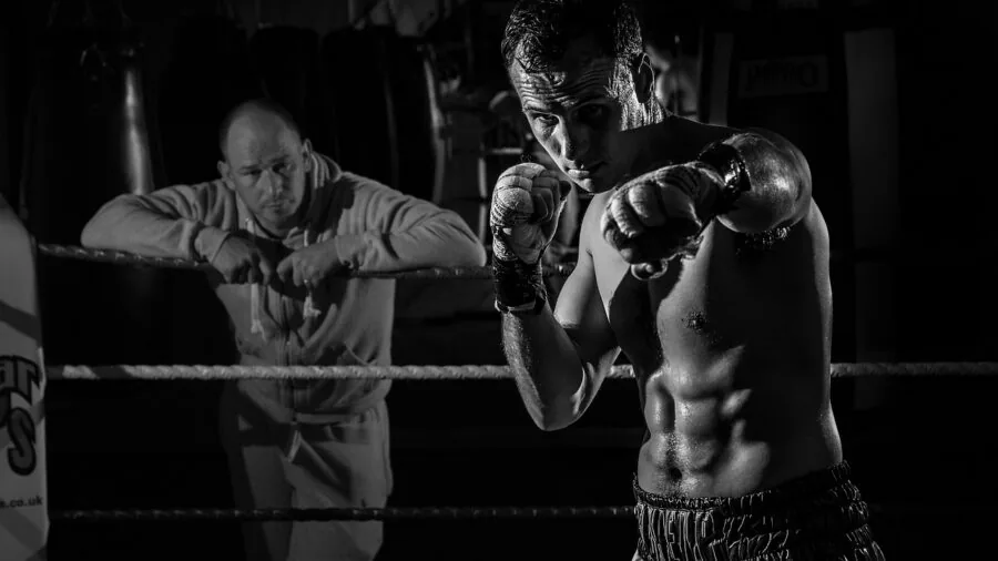 Athletic person practicing punches on heavy bag in boxing gym during training session