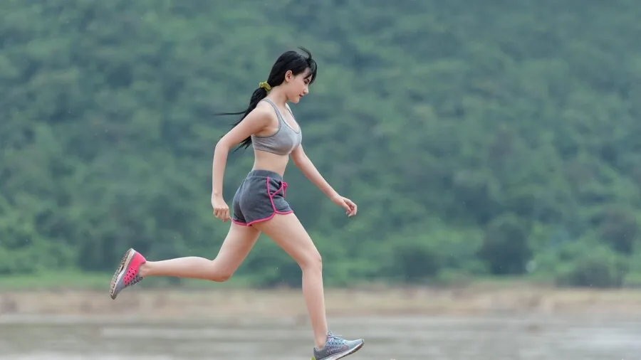 Athletic person running outdoors in daylight, demonstrating proper form and movement
