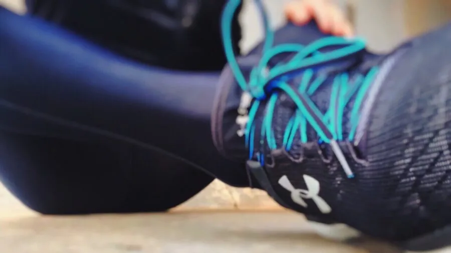 Athletic runner checking waistband fit while jogging on sunny trail