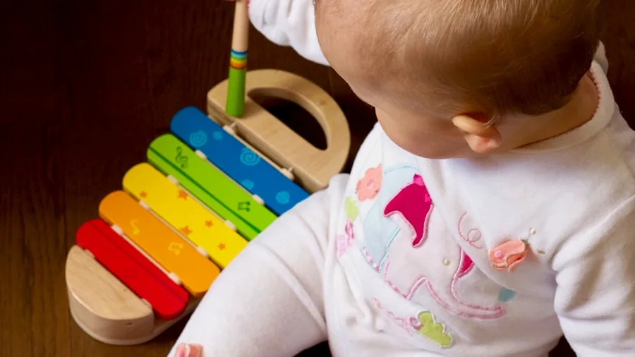 Baby exploring age-appropriate toy, focused expression showing engagement and learning through play