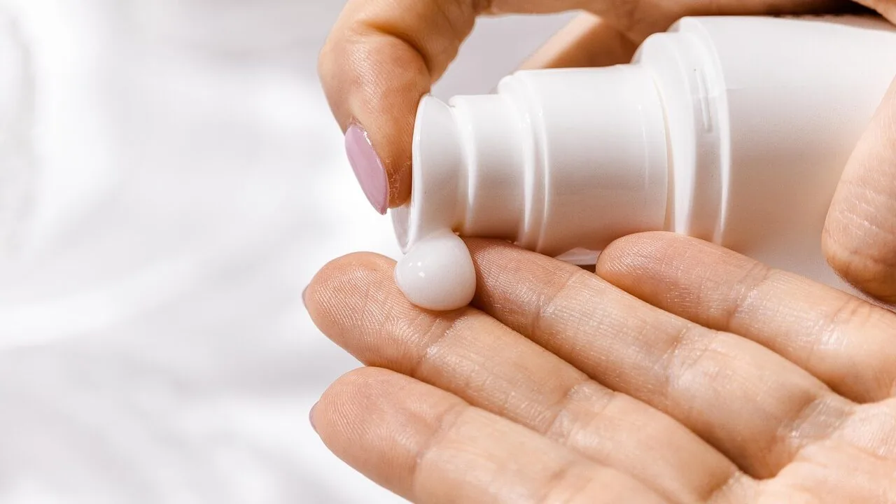 Baby lotion bottle with product applied to infant skin, showing moisturizing cream texture