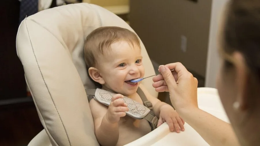 Baby playing with toys on a soft mat, showing real-life messiness of infant play and need for washable materials