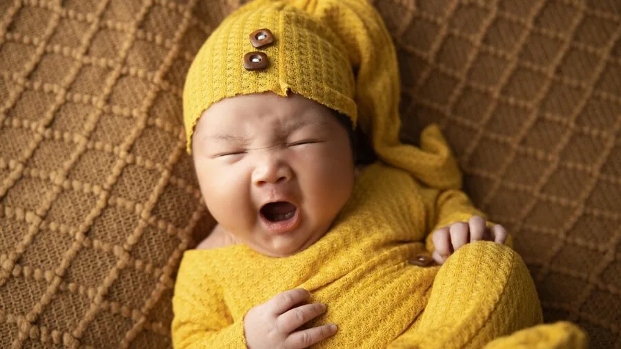 Baby reaching toward colorful textured objects while crawling on floor, engaging senses through play
