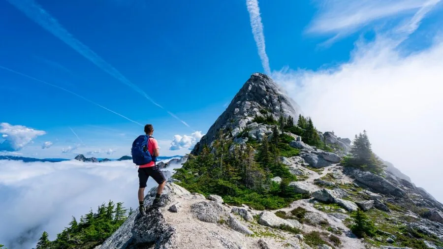 Backpacker with lightweight gear hiking through mountain wilderness trail during daytime