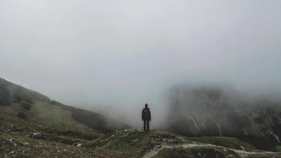 Backpacker with loaded pack hiking uphill on mountain trail during daytime