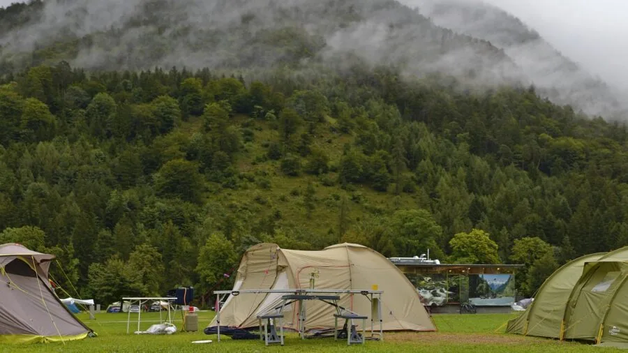 Backpacking tent setup during rainfall in natural outdoor environment