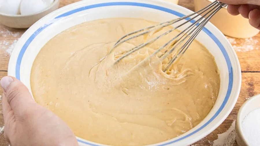 Baker whisking ingredients in ceramic bowl during food preparation