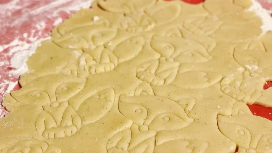 Baker's hands taking freshly baked golden cookies off a rimmed baking sheet in a home kitchen