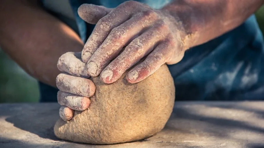 Baker's hands working with dough on a kitchen counter during food preparation