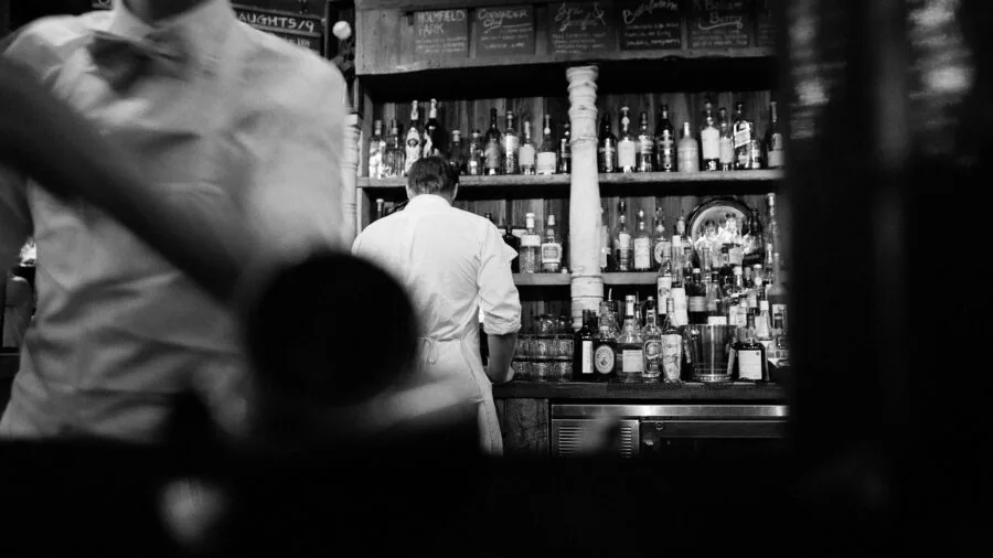 Bartender arranging bar tools and accessories while preparing cocktails at counter
