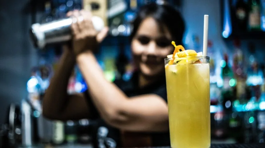 Bartender preparing multiple cocktails in a shaker for guests at a bar