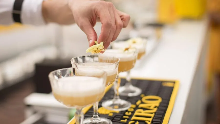 Bartender straining a cocktail drink into a glass at a home bar setup