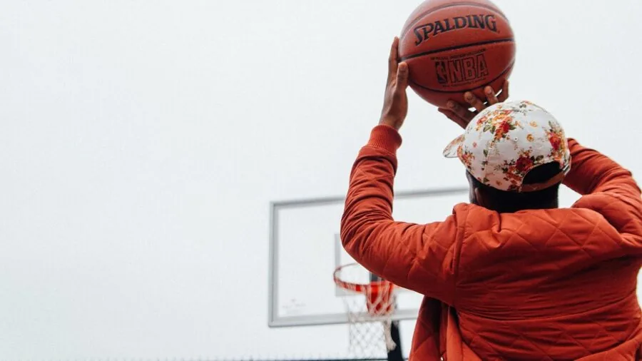 Basketball player taking a bank shot off the backboard during outdoor court gameplay